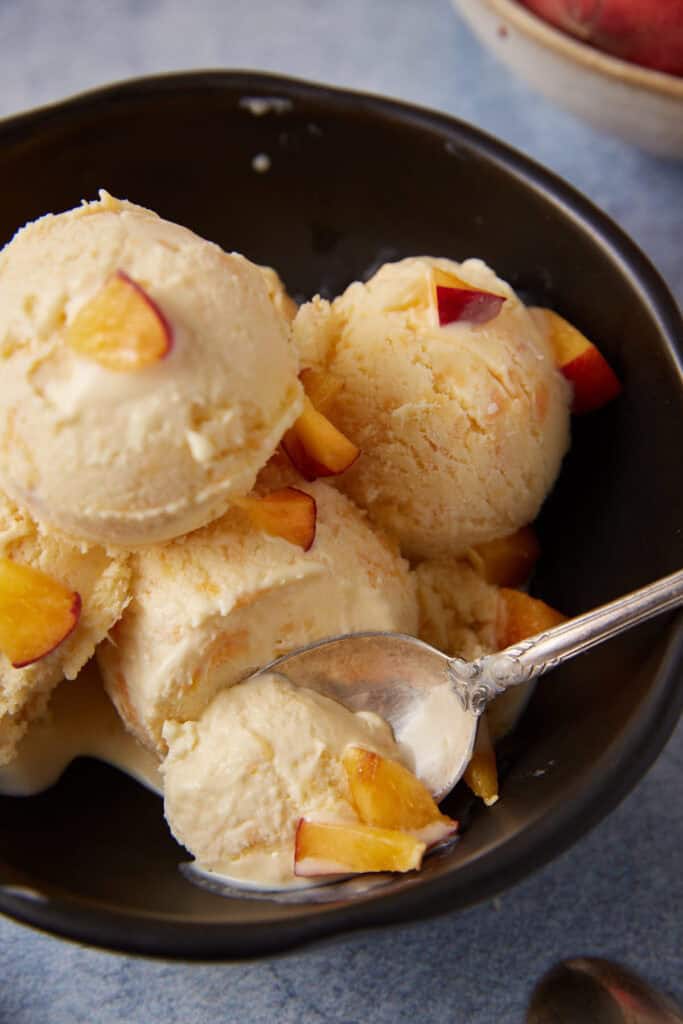 A spoon full of peach ice cream.