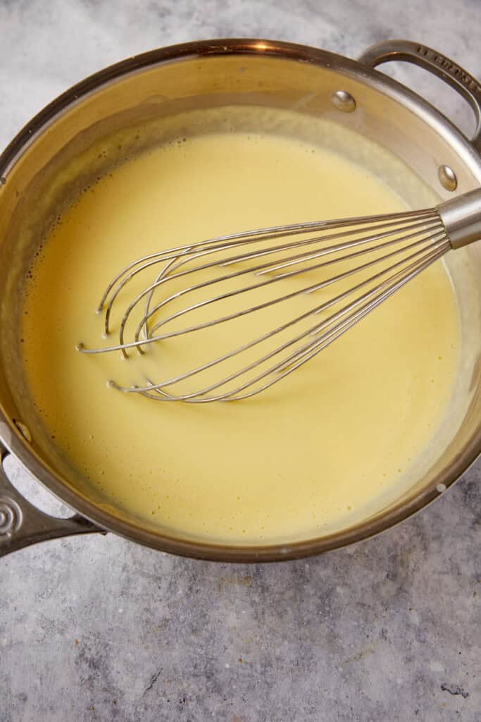 Custard cooked in a saucepan with a whisk.