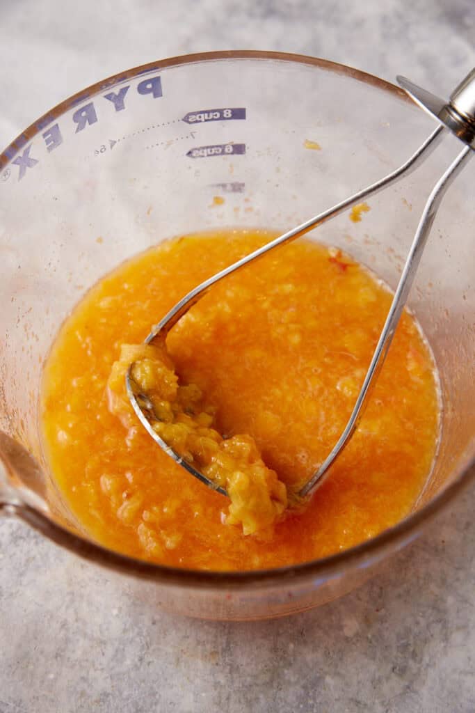 Peaches being mashed in a bowl.