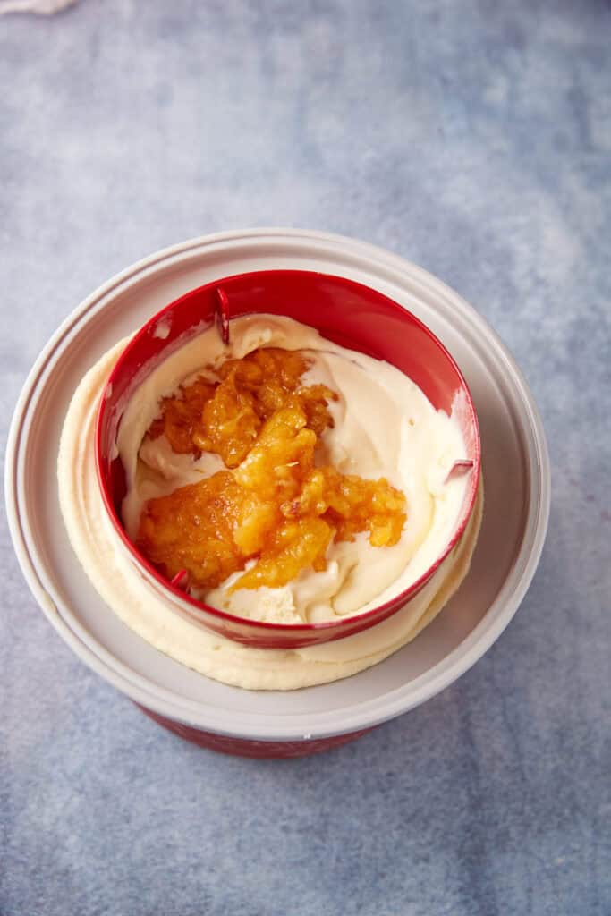 Peaches added to soft served ice cream in an ice cream maker.