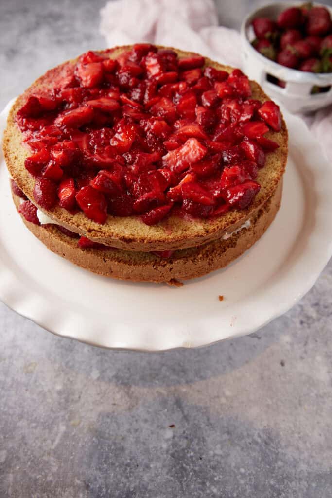 Strawberries on top of the layers before it has been frosted.