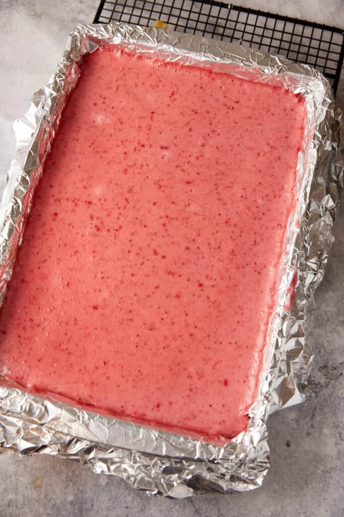 Strawberry filling on top of cheesecake in a pan.