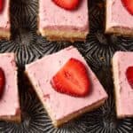 Strawberry cheesecake bars line up on a tray.