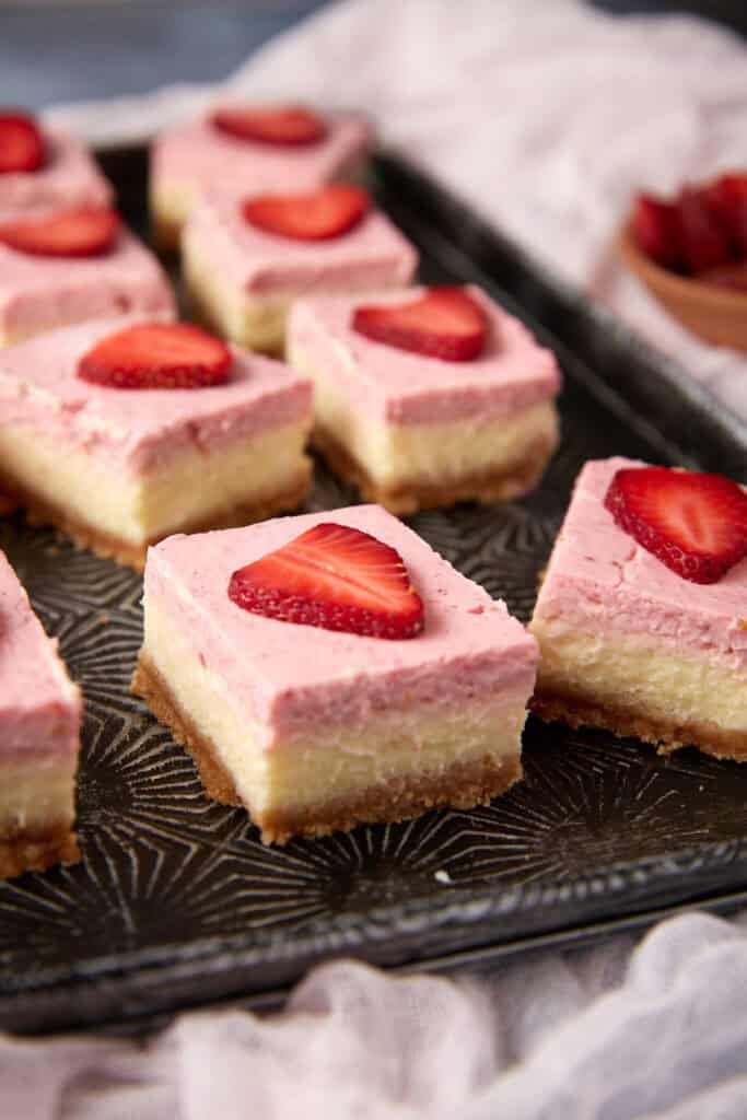 A dark tray with strawberry cream cheese bars.