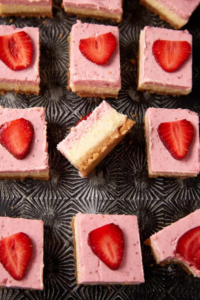 A tray of strawberry cheesecake bars with one turned on its side.