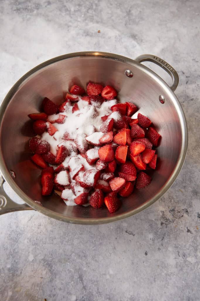 Strawberries and sugar in a saucepan.
