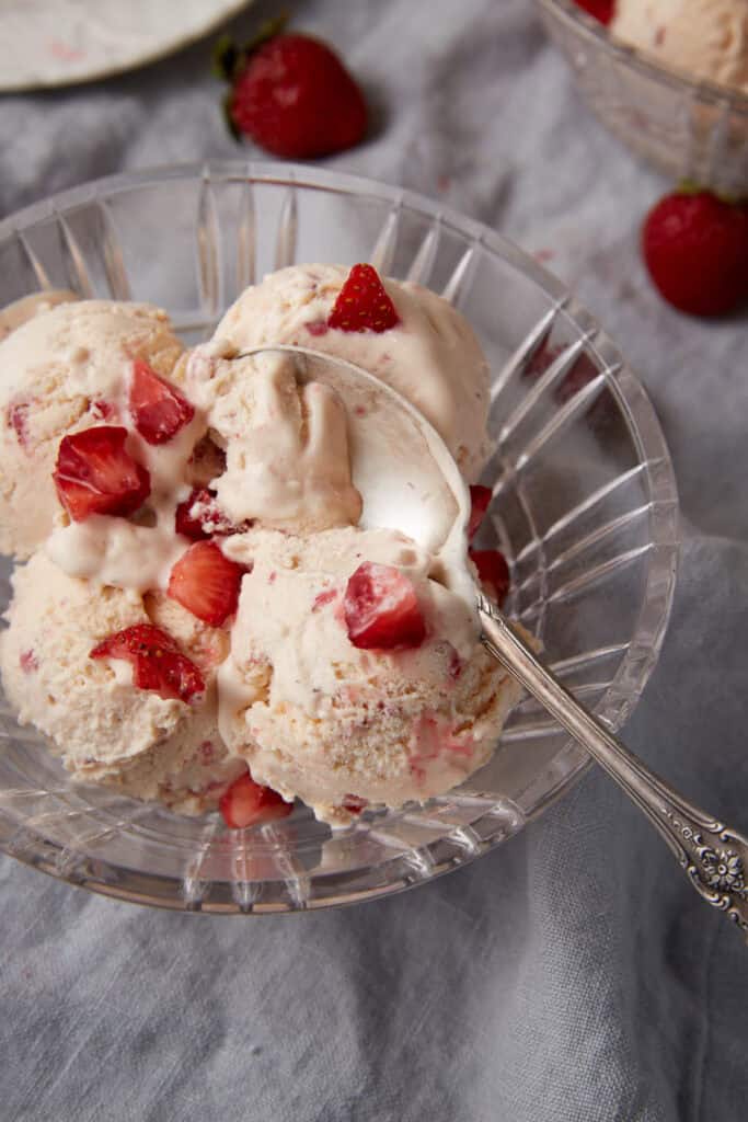 A bowl of strawberry ice cream with a spoon.