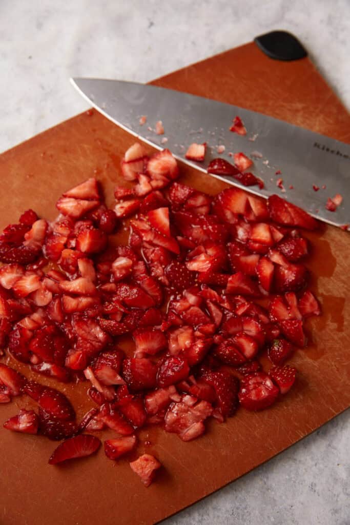 Cut strawberries on a cutting board.