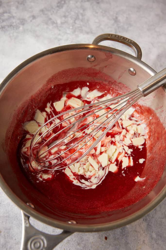 White chocolate added to a saucepan of strawberry syrup.