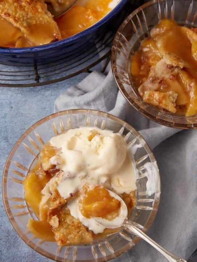 A glass bowl of peach cobbler and ice cream.