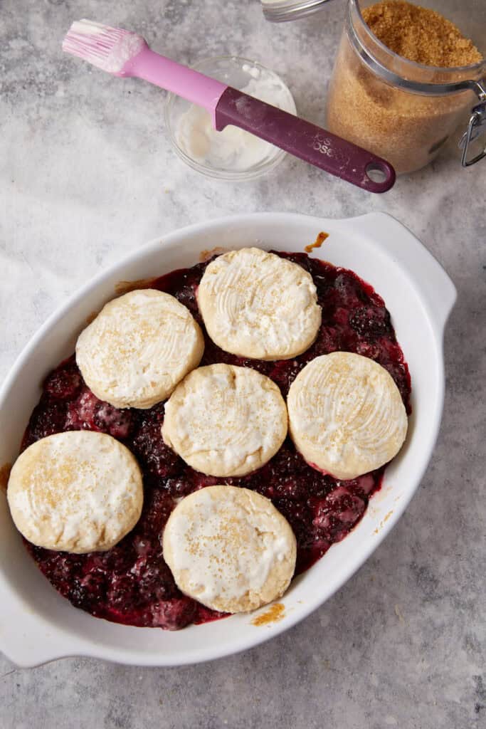 Biscuits on top of a partially cooked cobbler.