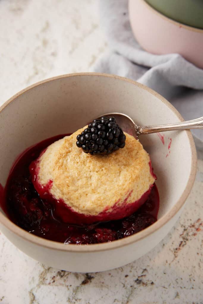 A bowl of blackberry cobbler with a biscuit on top.