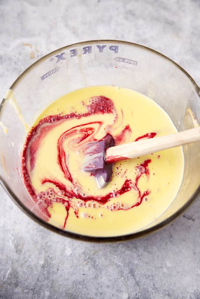 Blackberry syrup being swirled into a custard.