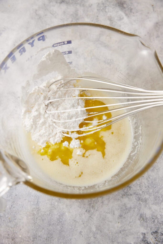 The ingredients for a vanilla sauce in a bowl with a whisk.
