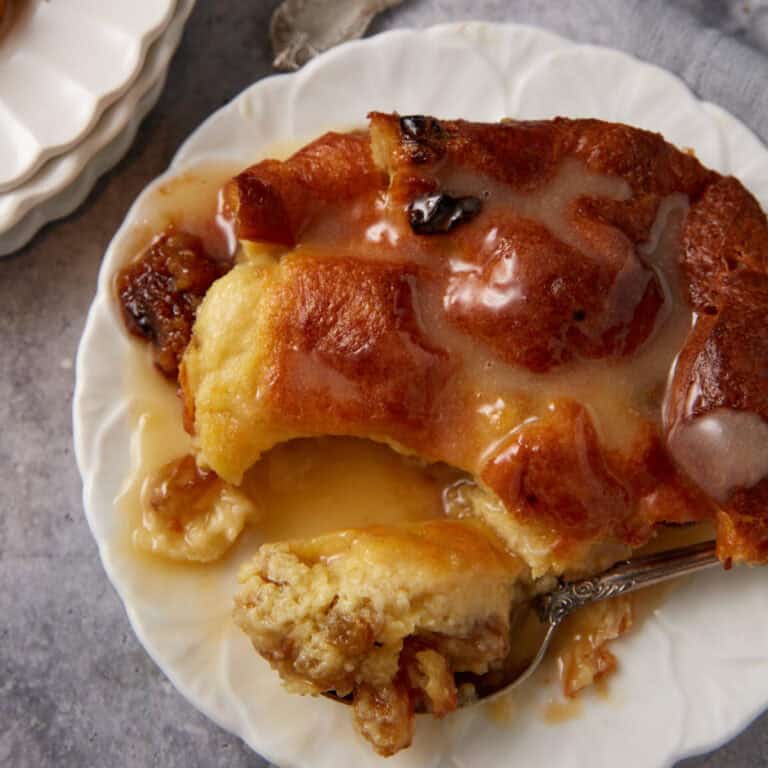 A single serving of bread pudding with vanilla sauce.