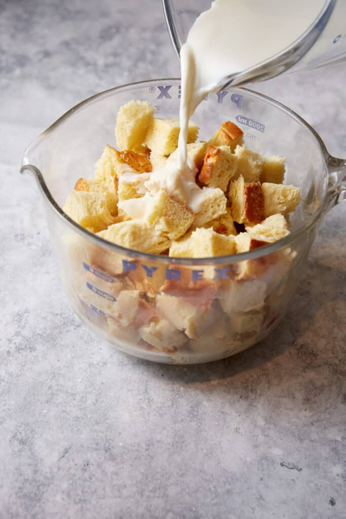 Custard being poured over bread cubes.