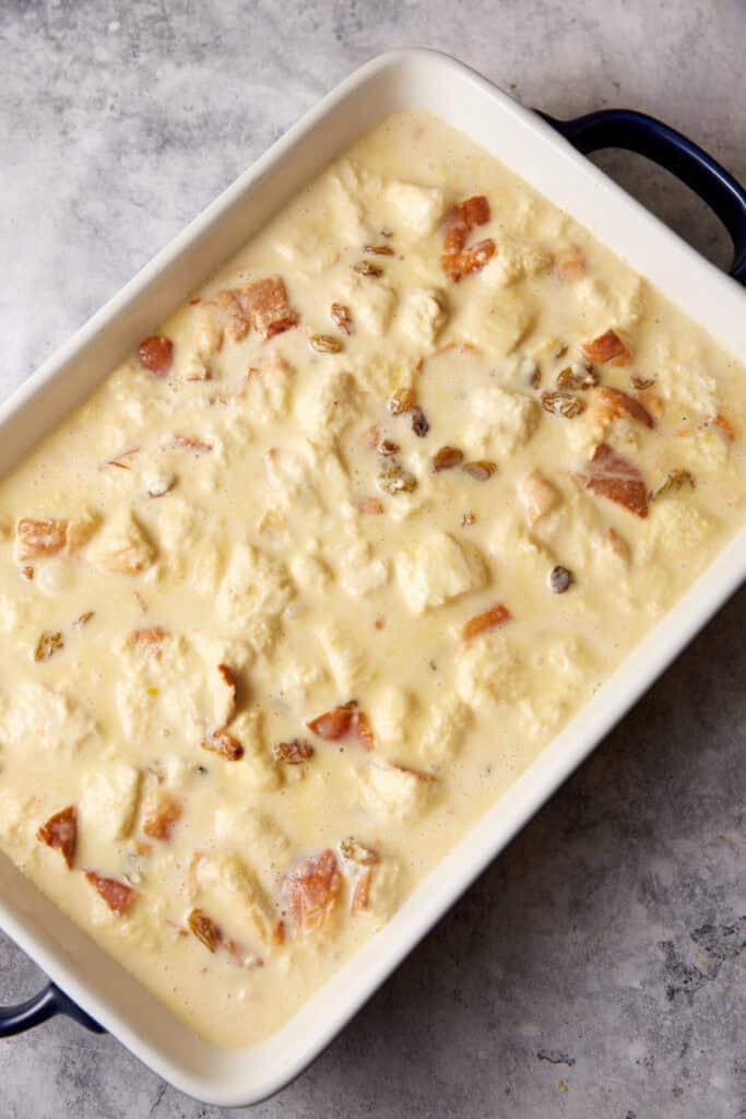 Bread and custard poured into a casserole dish.