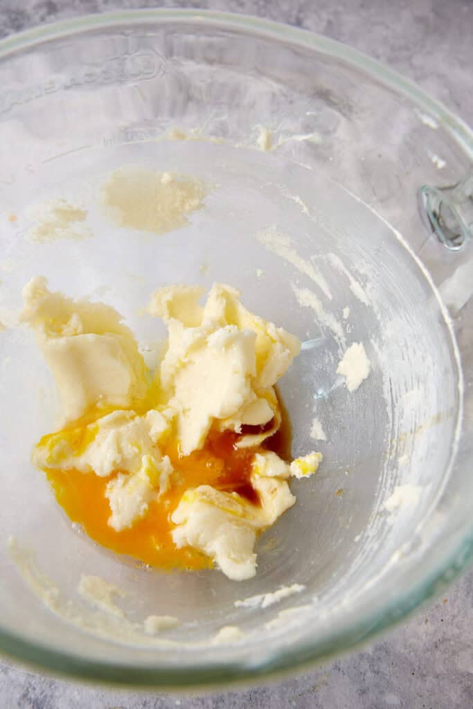 Eggs added to butter and sugar in a mixing bowl.