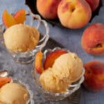 Three glass bowls of peach sorbet next to a bowl of peaches.