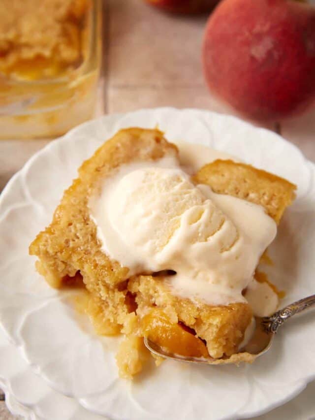 A serving of peach cobbler cake with a scoop of vanilla ice cream.