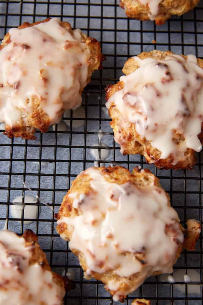 Apple fritters glazed on a black rack.