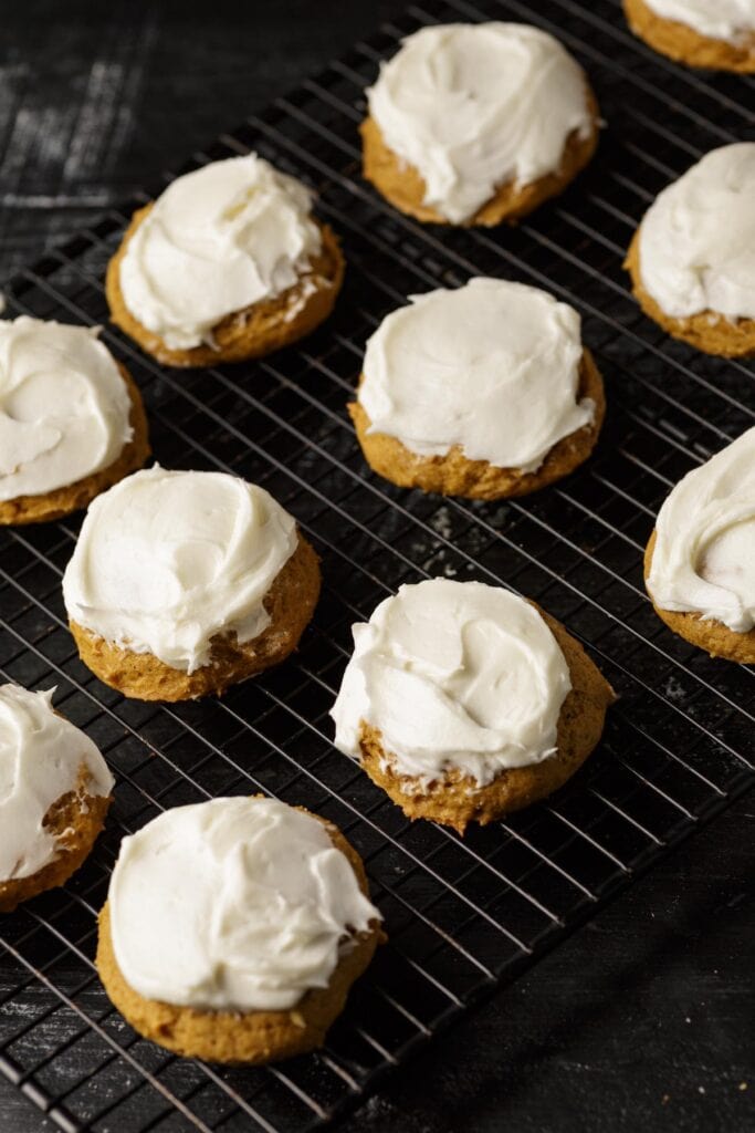 Frosted pumpkin cookies on a wire rack. 
