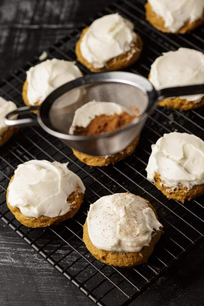 Pumpkin spice being sprinkled on cookies.