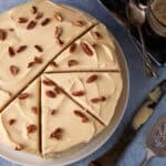 A caramel cake with pecans cut into slices.