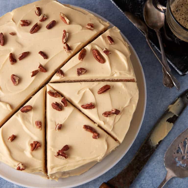 A caramel cake with pecans cut into slices.