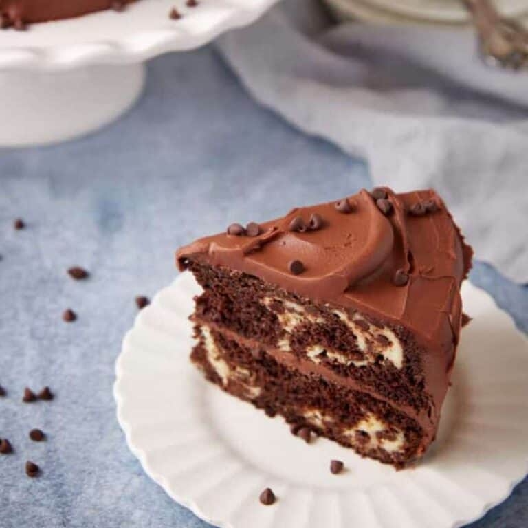 A slice of chocolate cream cheese cake with chocolate frosting on a plate.