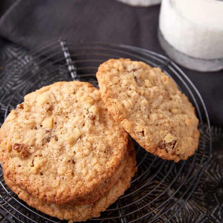 Stacked oatmeal coconut cookies next to a glass of milk.