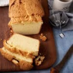 A sliced pound cake next to mugs.