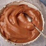 Chocolate mousse frosting in a bowl with a spoon.