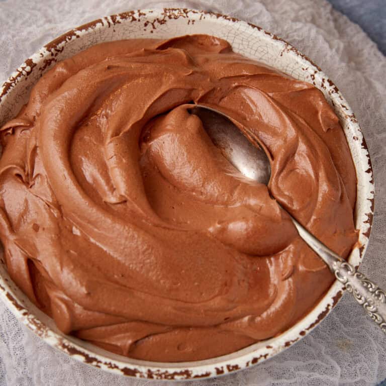 Chocolate mousse frosting in a bowl with a spoon.