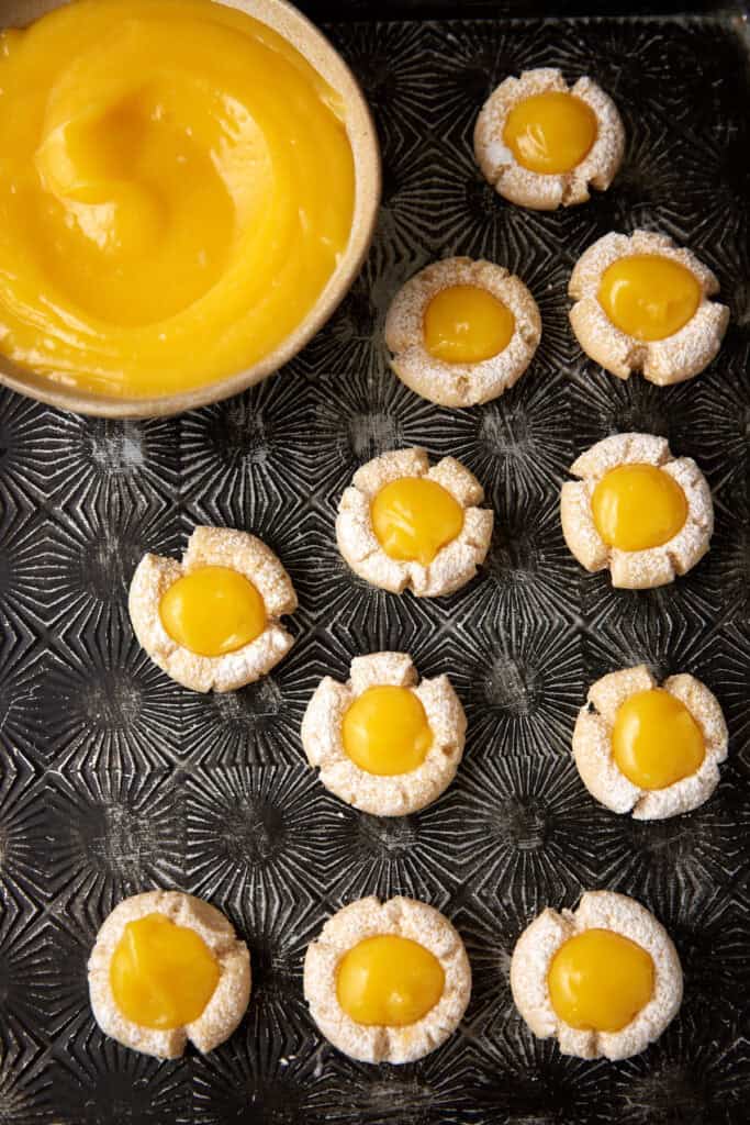 Lemon curd cookies next to a bowl of lemon curd.