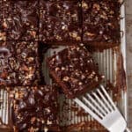 A piece of chocolae cake being removed form a pan.