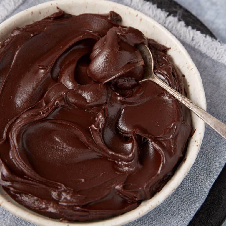 Chocolate frosting in a bowl with a spoon.