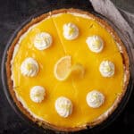 An entire lemon curd pie with whipped cream on top.