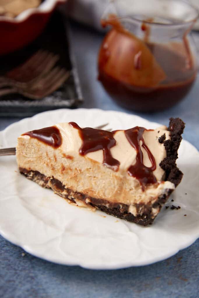 A single slice of turtle pie next to caramel sauce.