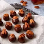 Pecan topped bourbon balls on parchment paper.