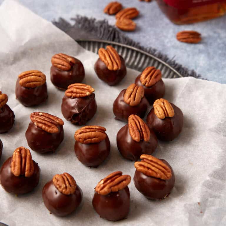 Pecan topped bourbon balls on parchment paper.