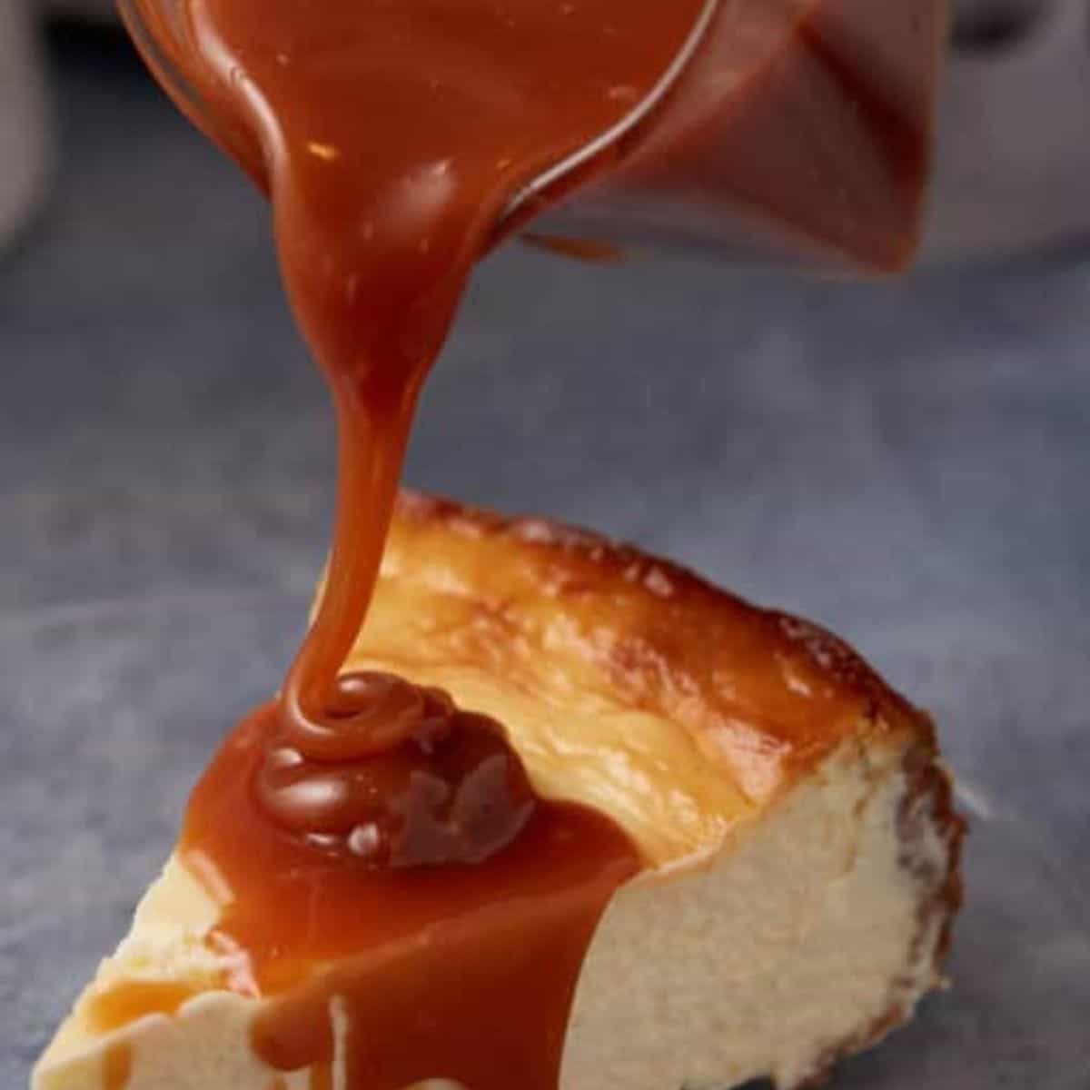 Caramel sauce being poured over a slice of cheesecake.