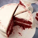 A red velvet layer cake cut into slices on a cake stand.