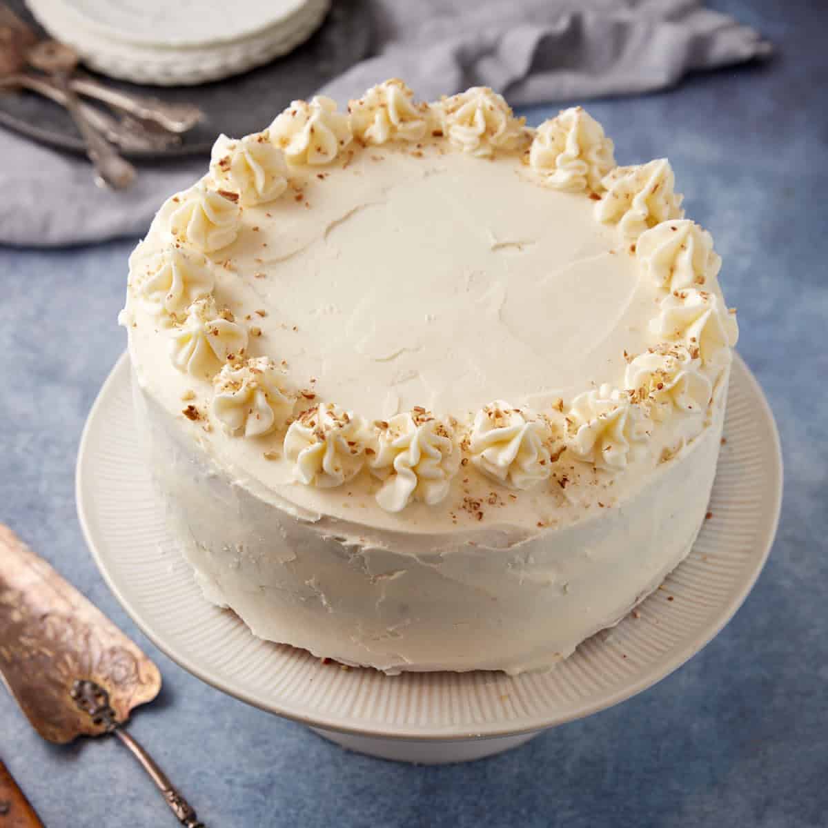 A frosted sweet potato cake on a platter with cream cheese frosting.