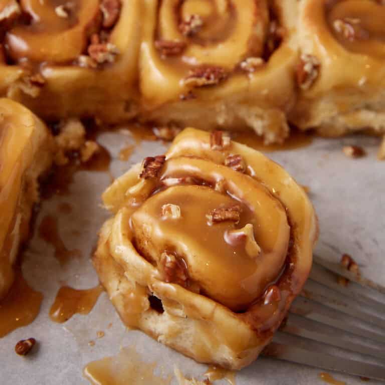 close up of a caramel cinnamon roll on a baking sheet.