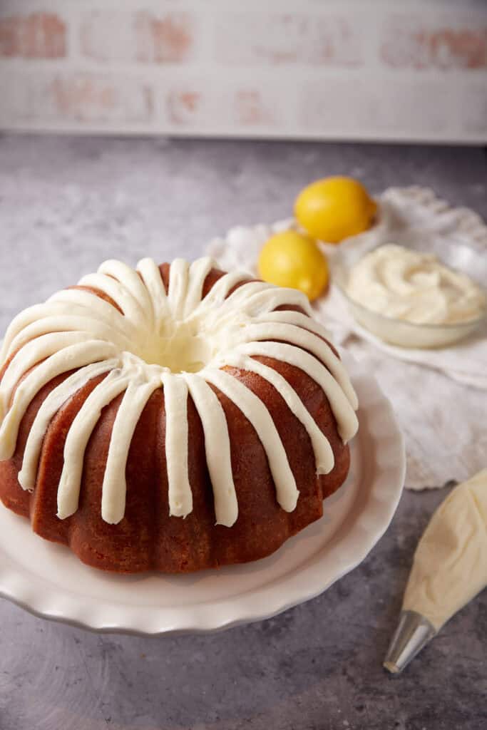 frosted lemon bundt cake on a white plate.