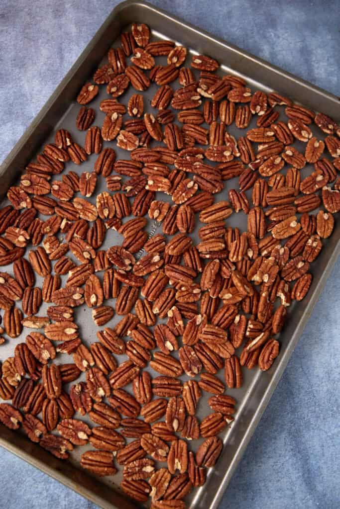pecans spread out on a baking sheet. 