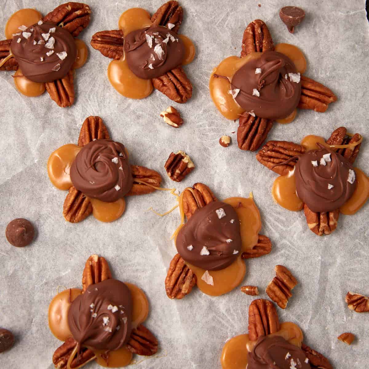 close up of pecan turtles on top of parchment paper.