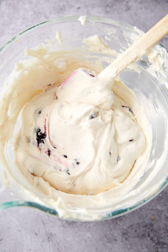 blackberry cream cheese frosting in a glass bowl with a spatula.