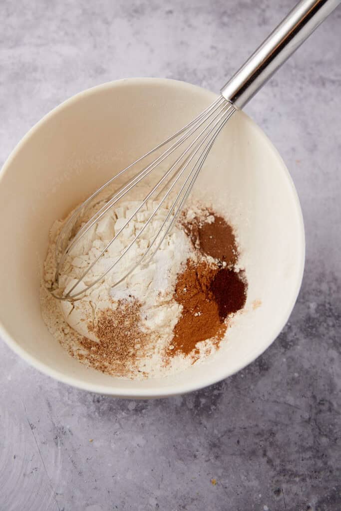 blackberry jam cake spices in a bowl with a whisk.